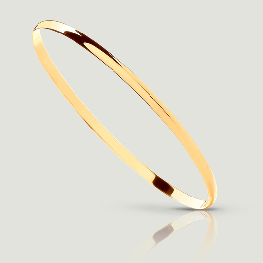 A close-up image of a 9ct yellow gold D-shaped bangle, 3mm wide. The bangle is shown balancing diagonally on one side, revealing a smooth, flat, interior surface for comfortable wear. Its smooth, tactile exterior is gently curved, providing a sleek and stylish look. This elegant piece of jewellery is a timeless addition to any collection, perfect for adding sophistication to any ensemble.