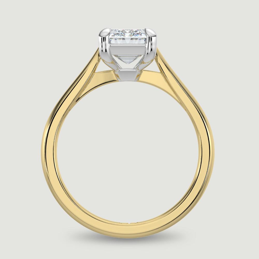 An 18ct yellow gold single stone diamond engagement ring, set with a lab-grown emerald cut diamond held in a platinum four claw setting. Viewed from the side.