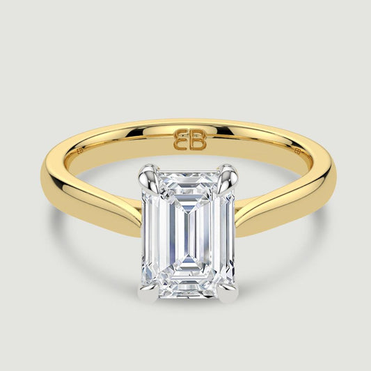 An 18ct yellow gold single stone diamond engagement ring, set with a lab-grown emerald cut diamond held in a platinum four claw setting. Viewed from above.