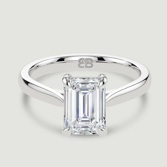 A platinum single stone diamond engagement ring, set with a lab-grown emerald cut diamond held in a four claw setting. Viewed from above.
