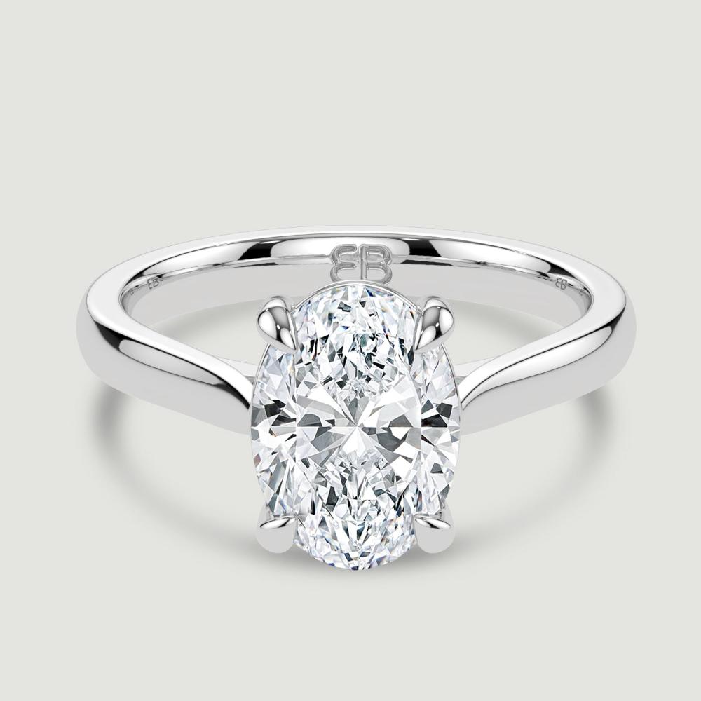 A platinum single stone diamond engagement ring, set with a lab-grown oval shape diamond held in a four claw setting. Viewed from above.