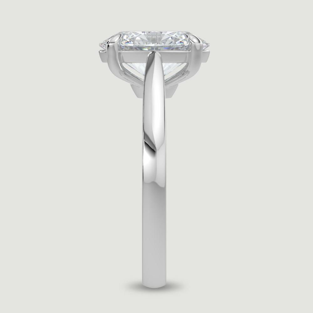 A platinum single stone diamond engagement ring, set with a lab-grown oval shape diamond held in a four claw setting. Viewed from the edge.
