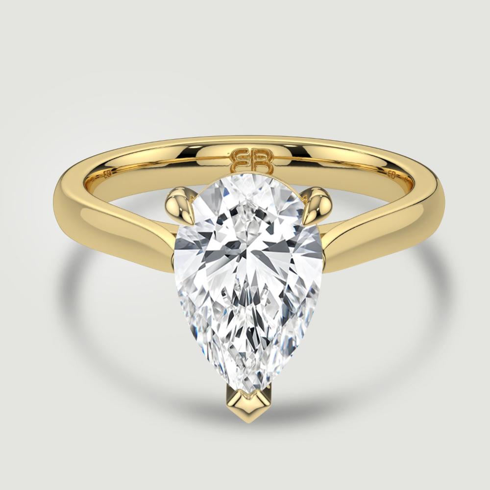 An 18ct yellow gold single stone diamond engagement ring, set with a lab-grown pear shape diamond held in a three claw setting. Viewed from above.