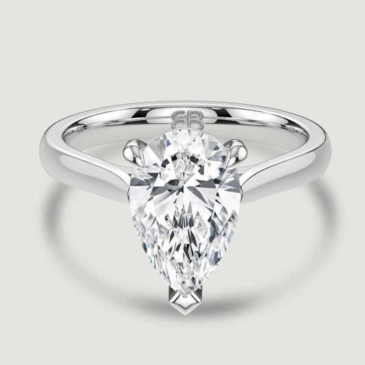 A platinum single stone diamond engagement ring, set with a lab-grown pear shape diamond held in a three claw setting. Viewed from above.