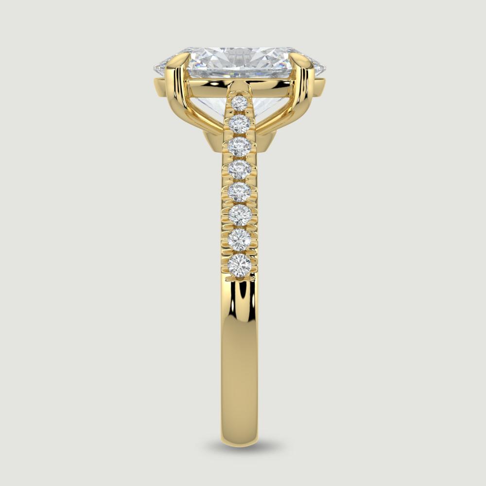 An 18ct yellow gold single stone diamond engagement ring, with micro-pavé set shoulders set with a lab-grown oval shape diamond held in a four claw setting. Viewed from the edge.