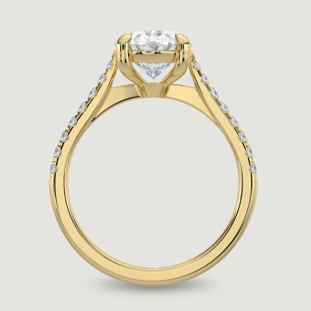 An 18ct yellow gold single stone diamond engagement ring, with micro-pavé set shoulders set with a lab-grown oval shape diamond held in a four claw setting. Viewed from the side.