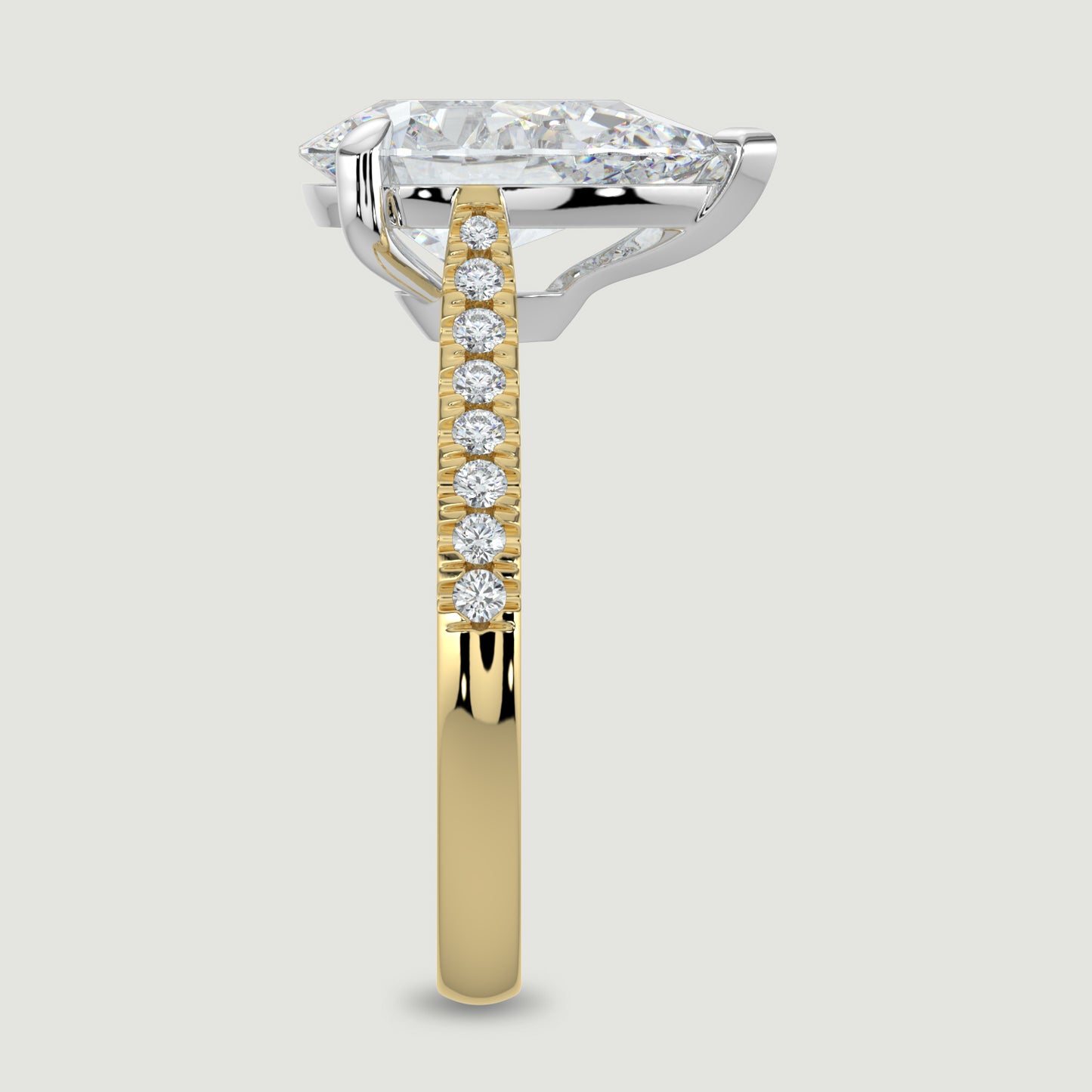An 18ct yellow gold single stone diamond engagement ring, with micro-pavé set shoulders set with a lab-grown pear shape diamond held in a platinum three claw setting. Viewed from the edge.