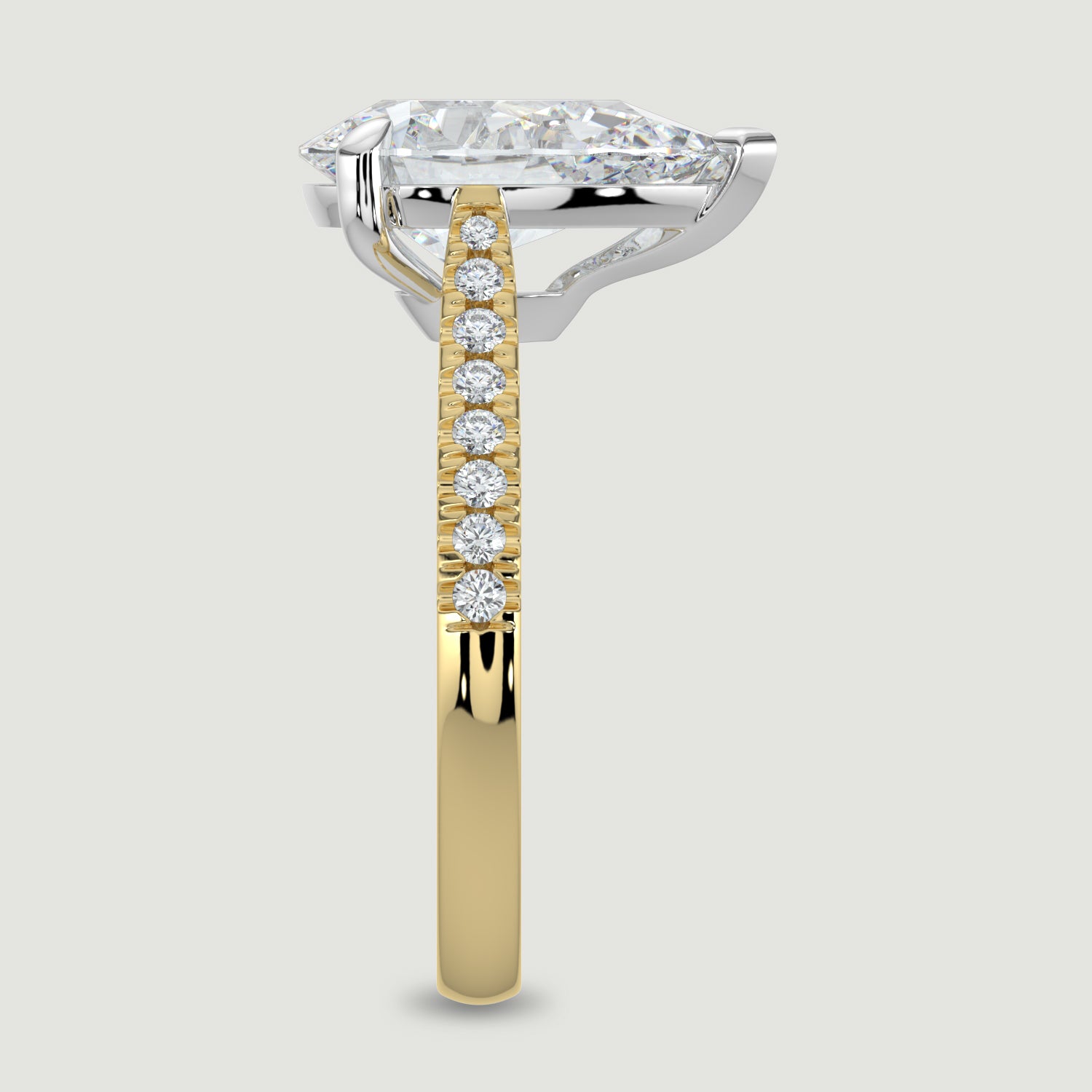 An 18ct yellow gold single stone diamond engagement ring, with micro-pavé set shoulders set with a lab-grown pear shape diamond held in a platinum three claw setting. Viewed from the edge.