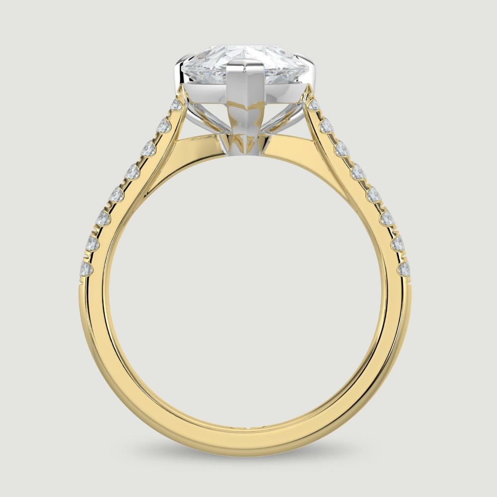 An 18ct yellow gold single stone diamond engagement ring, with micro-pavé set shoulders set with a lab-grown pear shape diamond held in a platinum three claw setting. Viewed from the side.