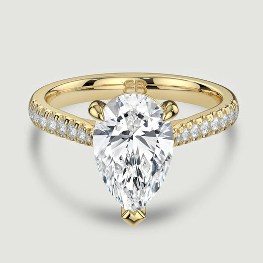 An 18ct yellow gold single stone diamond engagement ring, with micro-pavé set shoulders set with a lab-grown pear shape diamond held in a three claw setting. Viewed from above.
