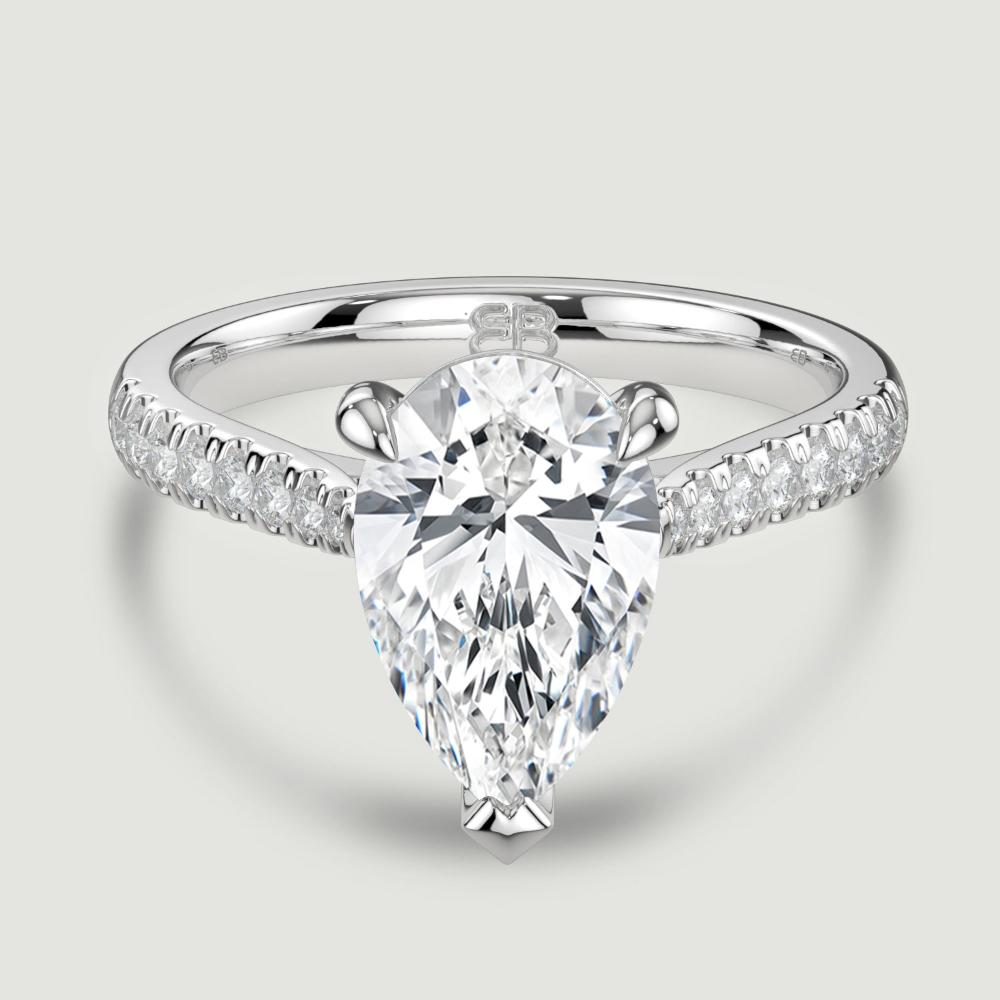 A platinum single stone diamond engagement ring, with micro-pavé set shoulders set with a lab-grown pear shape diamond held in a three claw setting. Viewed from above.