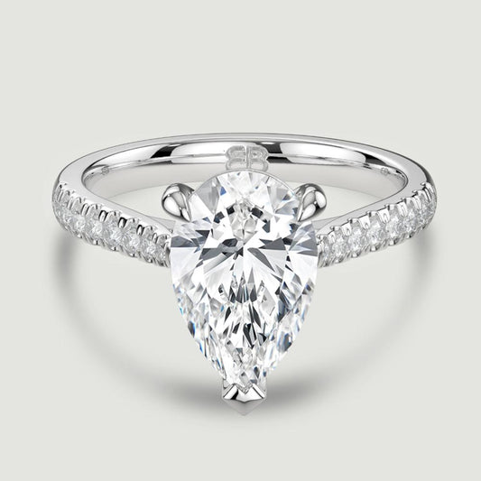 A platinum single stone diamond engagement ring, with micro-pavé set shoulders set with a lab-grown pear shape diamond held in a three claw setting. Viewed from above.