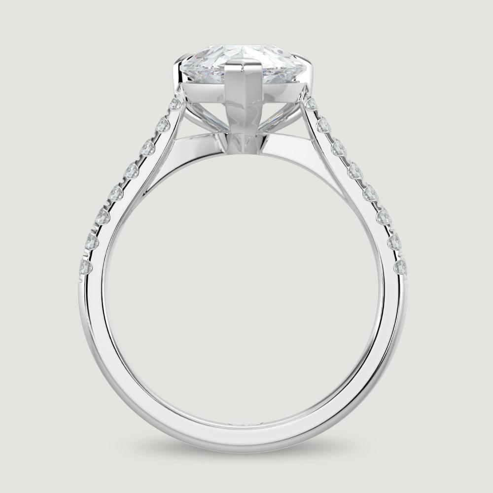 A platinum single stone diamond engagement ring, with micro-pavé set shoulders set with a lab-grown pear shape diamond held in a three claw setting. Viewed from the side.