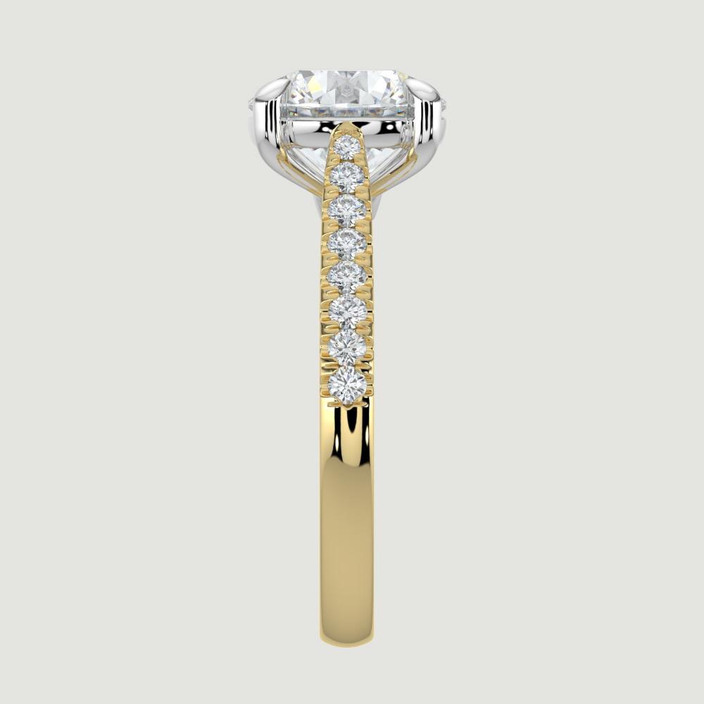 An 18ct yellow gold single stone diamond engagement ring, with micro-pavé set shoulders set with a lab-grown round brilliant diamond held in a platinum four claw setting. Viewed from the edge.