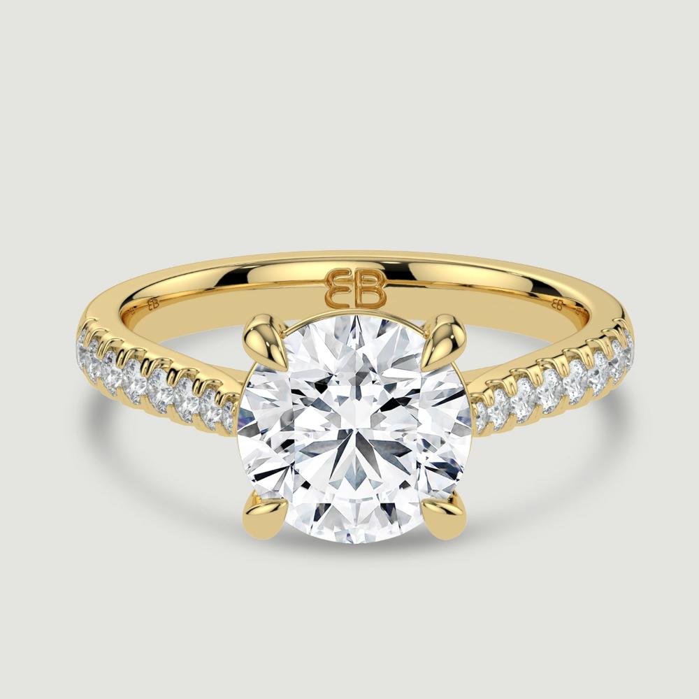 An 18ct yellow gold single stone diamond engagement ring, with micro-pavé set shoulders set with a lab-grown round brilliant diamond held in a four claw setting. Viewed from above.