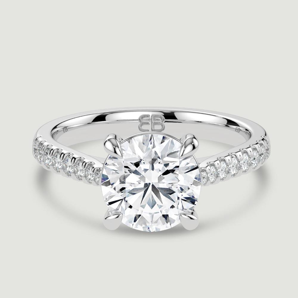 A platinum single stone diamond engagement ring, with micro-pavé set shoulders set with a lab-grown round brilliant diamond held in a four claw setting. Viewed from above.