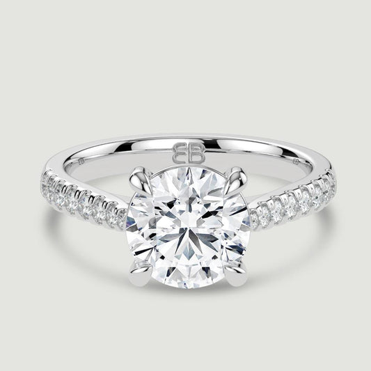 A platinum single stone diamond engagement ring, with micro-pavé set shoulders set with a lab-grown round brilliant diamond held in a four claw setting. Viewed from above.