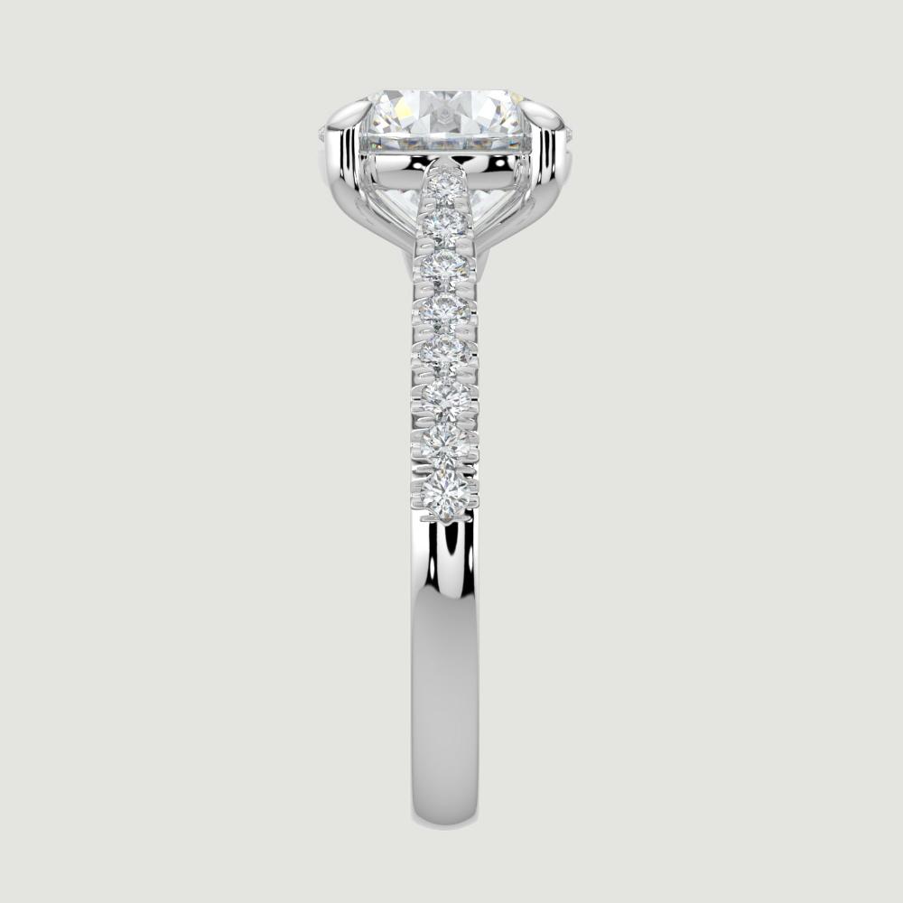 A platinum single stone diamond engagement ring, with micro-pavé set shoulders set with a lab-grown round brilliant diamond held in a four claw setting. Viewed from the edge.