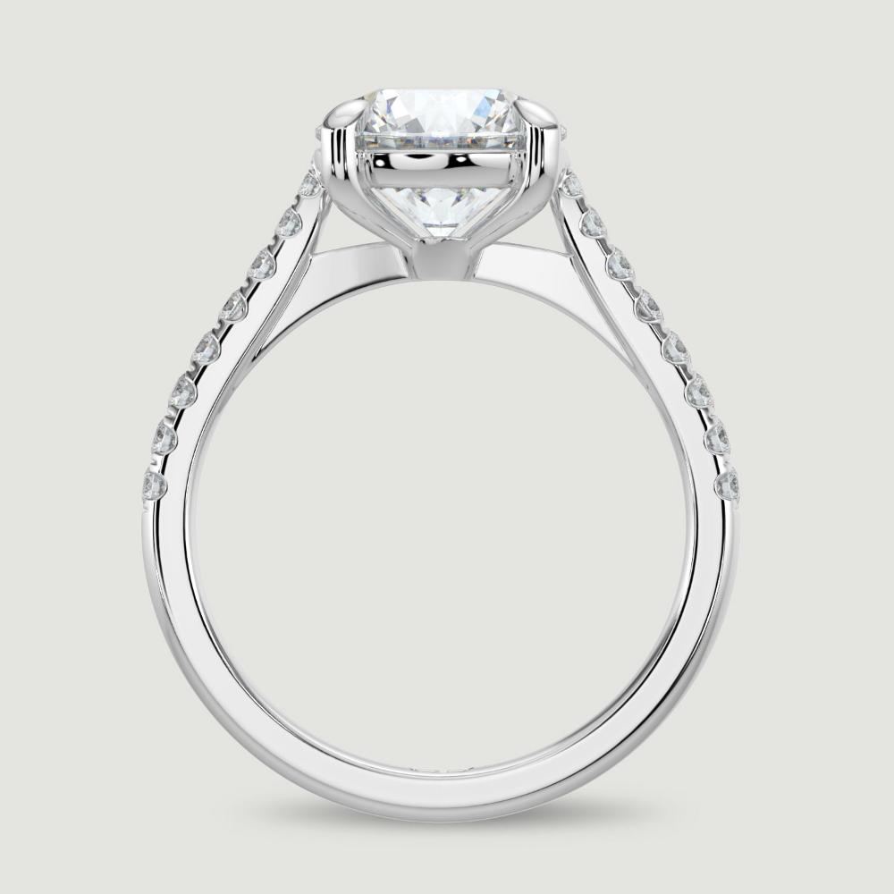 A platinum single stone diamond engagement ring, with micro-pavé set shoulders set with a lab-grown round brilliant diamond held in a four claw setting. Viewed from the side.