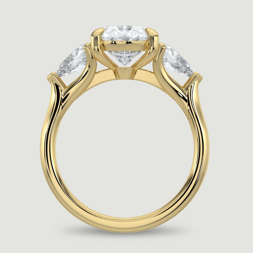 An 18ct yellow gold three stone diamond engagement ring, set with a lab-grown oval shape diamond centre stone held in a four claw setting flanked by a pear shaped lab-grown diamond on either side, held in three claws. Viewed from the side.