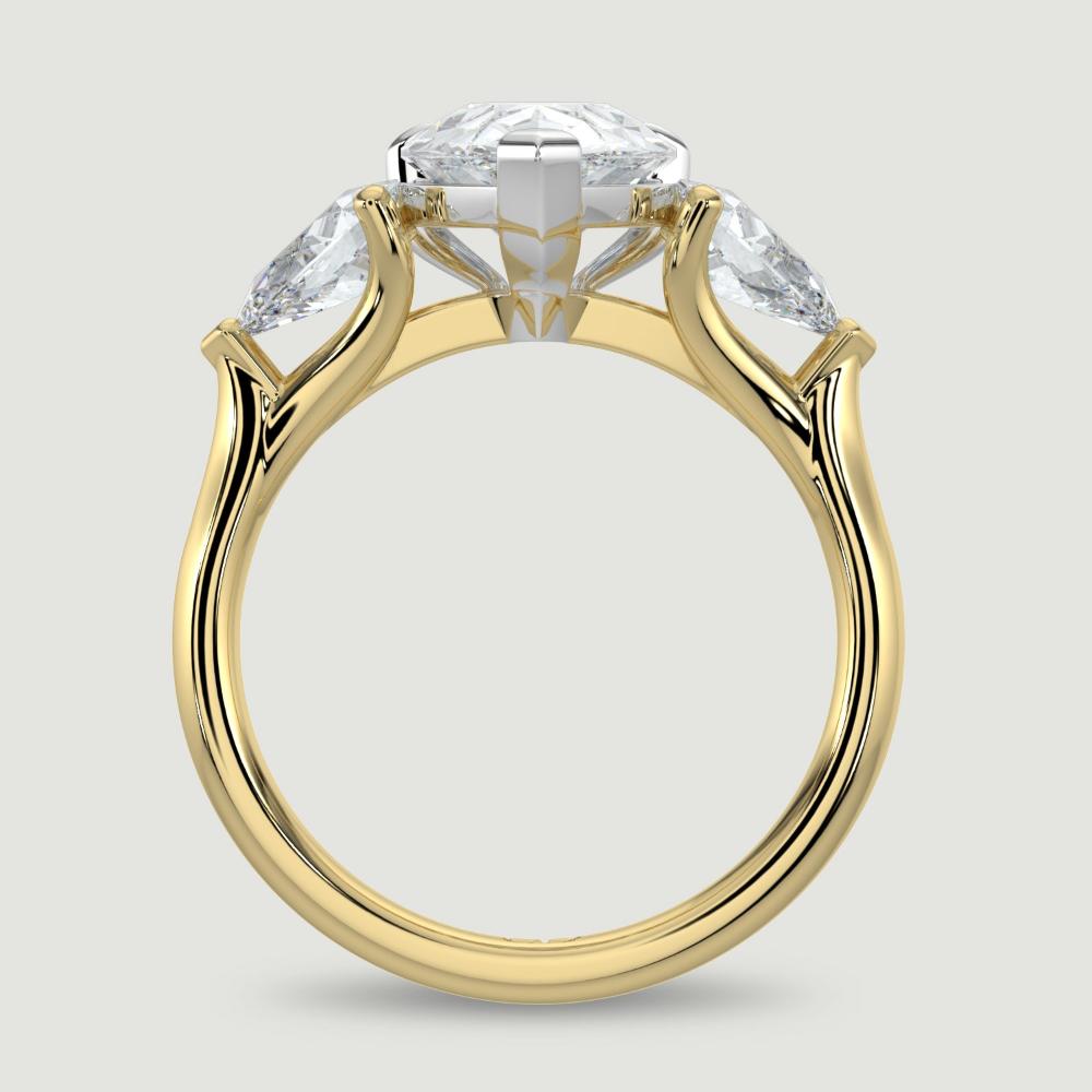 An 18ct yellow gold three stone diamond engagement ring, set with a lab-grown pear shape diamond centre stone held in a platinum three claw setting flanked by a pear shaped lab-grown diamond on either side, held in three claws. Viewed from the side.