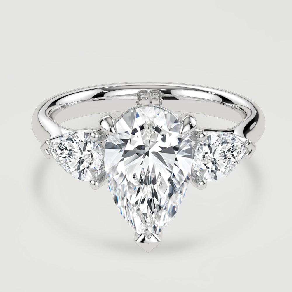 A platinum three stone diamond engagement ring, set with a lab-grown pear shape diamond centre stone held in a three claw setting flanked by a pear shaped lab-grown diamond on either side, held in three claws. Viewed from above.
