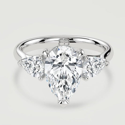 A platinum three stone diamond engagement ring, set with a lab-grown pear shape diamond centre stone held in a three claw setting flanked by a pear shaped lab-grown diamond on either side, held in three claws. Viewed from above.