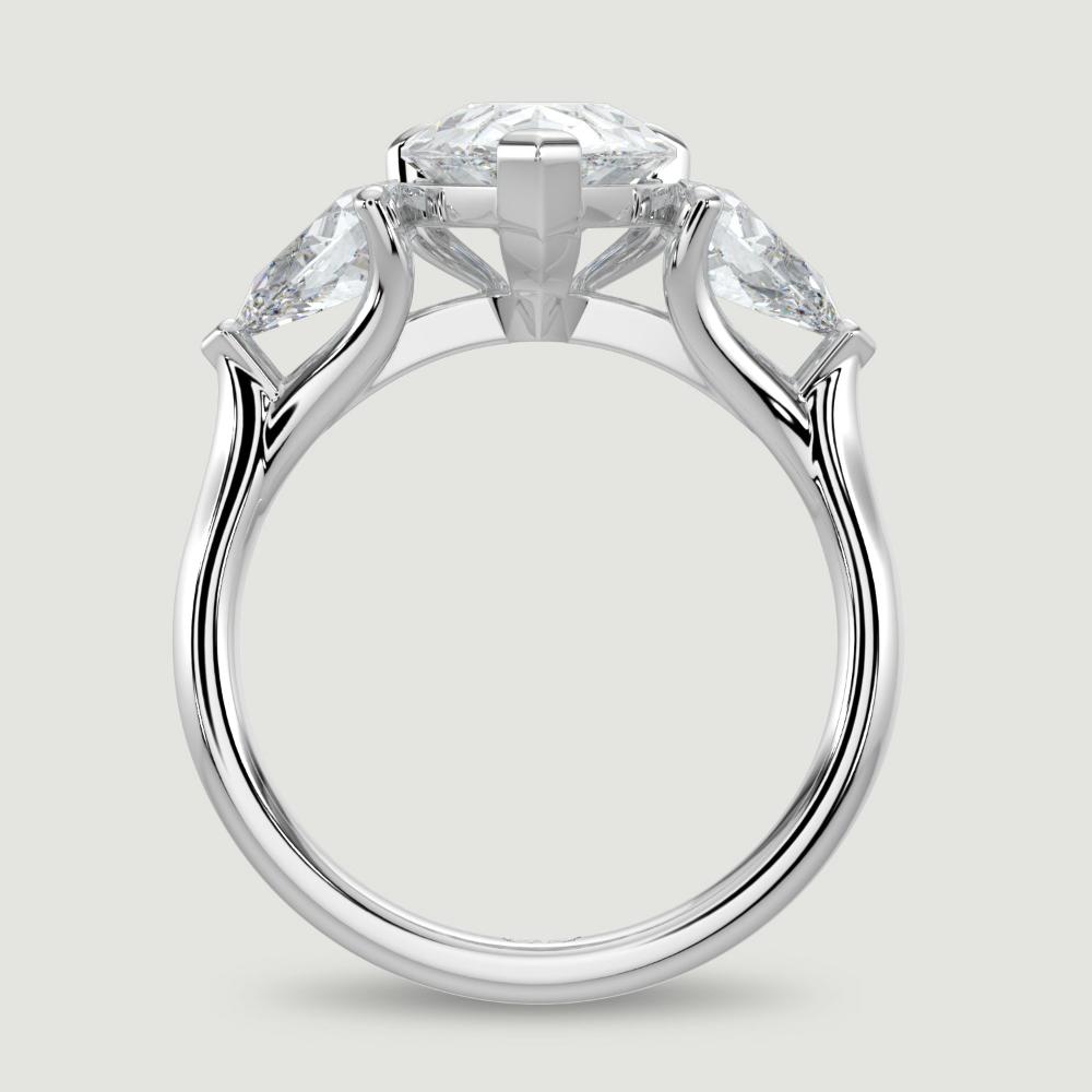 A platinum three stone diamond engagement ring, set with a lab-grown pear shape diamond centre stone held in a three claw setting flanked by a pear shaped lab-grown diamond on either side, held in three claws. Viewed from the side.