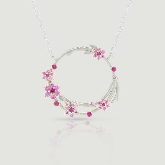sakura blossom circle pendant, circular branch in white gold with pink sapphire flower clusters in rose gold, on a fine white gold chain.