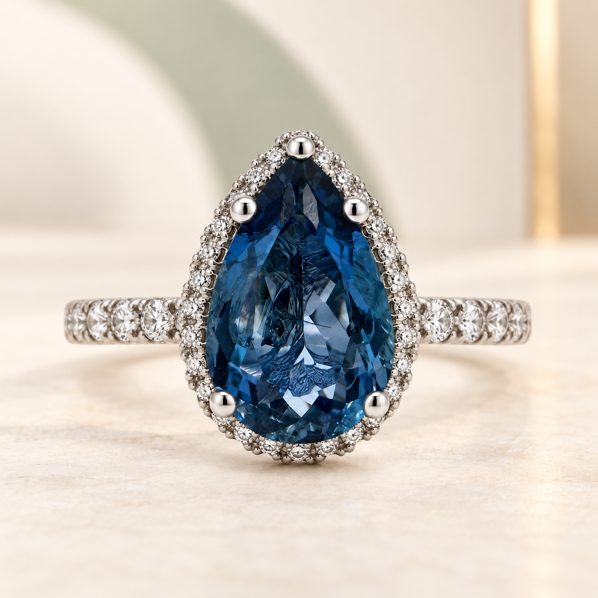 Pear-shaped deep-blue aquamarine and diamond halo ring in platinum.