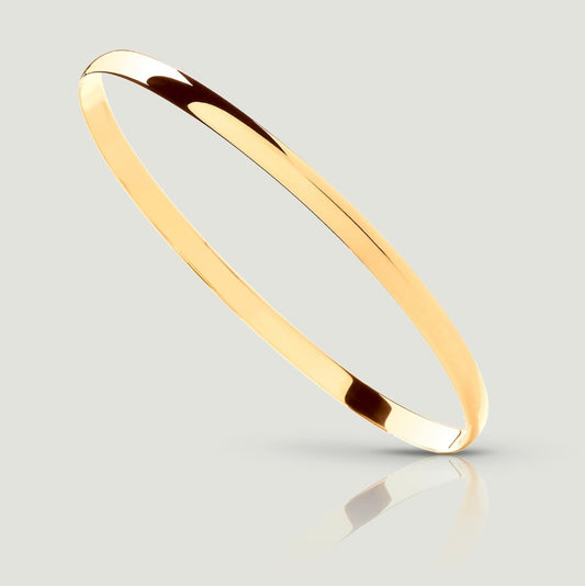 A close-up image of a 9ct yellow gold D-shaped bangle, 4mm wide. The bangle is shown balancing diagonally on one side, revealing a smooth, flat, interior surface for comfortable wear. Its smooth, tactile exterior is gently curved, providing a sleek and stylish look. This elegant piece of jewellery is a timeless addition to any collection, perfect for adding sophistication to any ensemble.
