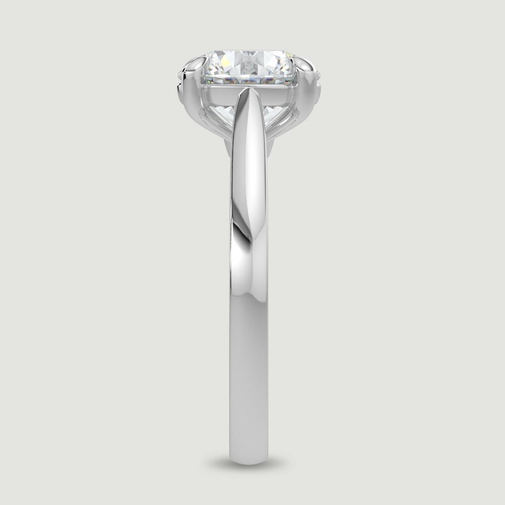 A platinum single stone diamond engagement ring, set with a lab-grown round brilliant diamond held in a four claw setting. Viewed from the edge.