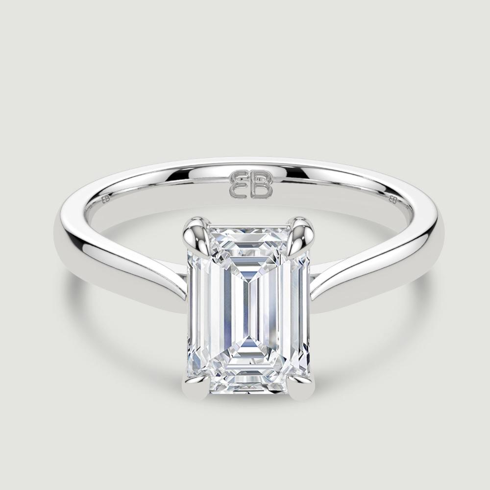 A platinum single stone diamond engagement ring, set with a lab-grown emerald cut diamond held in a four claw setting. Viewed from above.