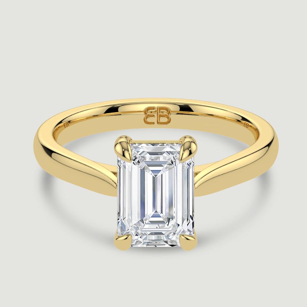 An 18ct yellow gold single stone diamond engagement ring, set with a lab-grown emerald cut diamond held in a four claw setting. Viewed from above.