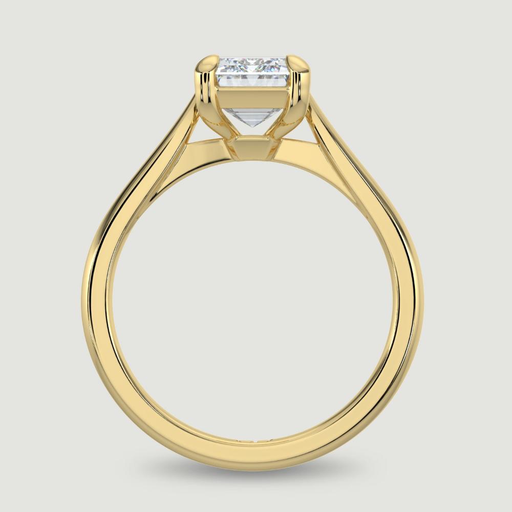 An 18ct yellow gold single stone diamond engagement ring, set with a lab-grown emerald cut diamond held in a four claw setting. Viewed from the side.