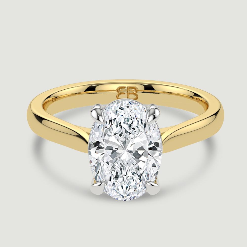 An 18ct yellow gold single stone diamond engagement ring, set with a lab-grown oval shape diamond held in a platinum four claw setting. Viewed from above.