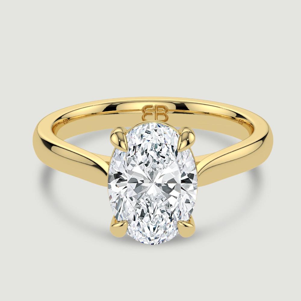 An 18ct yellow gold single stone diamond engagement ring, set with a lab-grown oval shape diamond held in a four claw setting. Viewed from above.