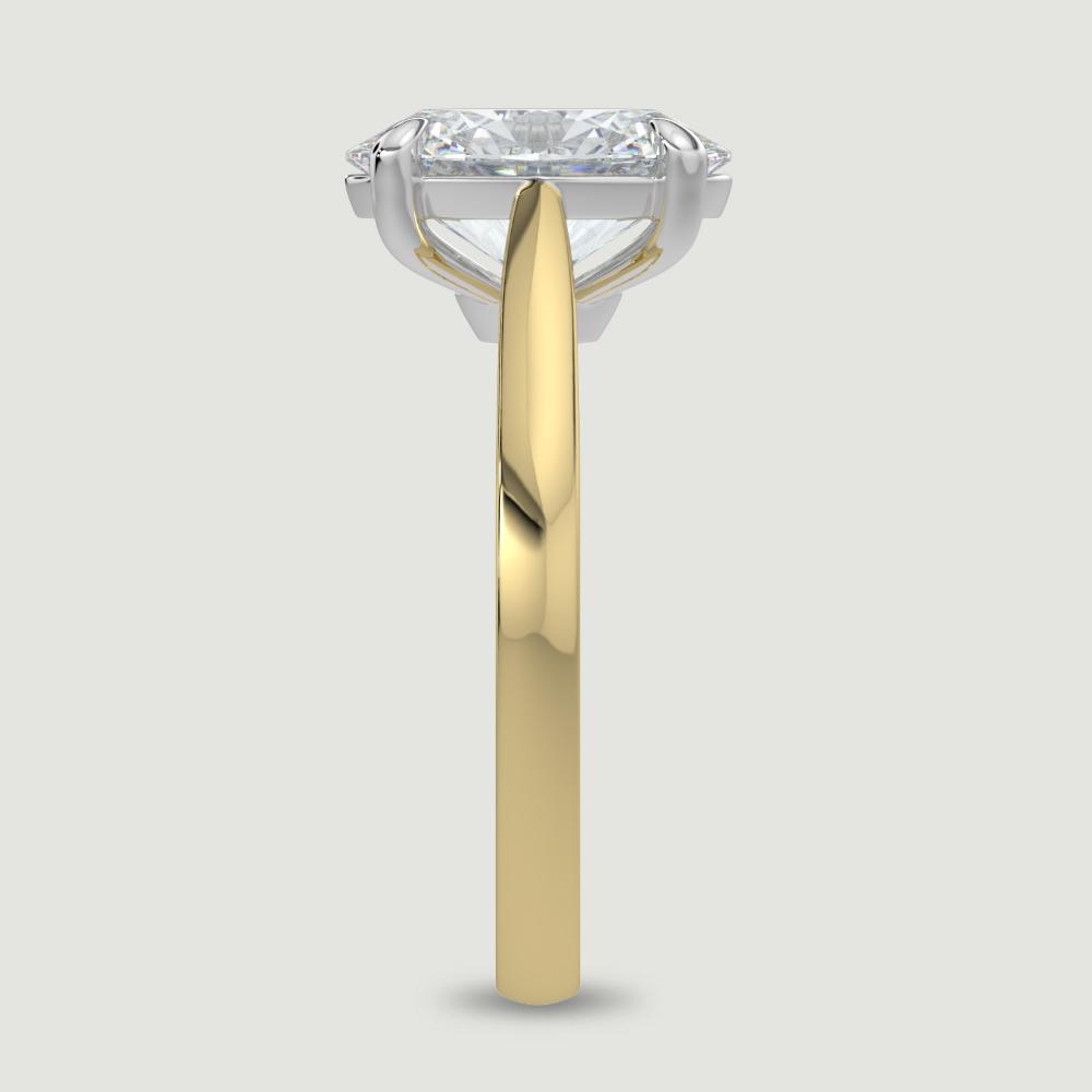 An 18ct yellow gold single stone diamond engagement ring, set with a lab-grown oval shape diamond held in a platinum four claw setting. Viewed from the edge.
