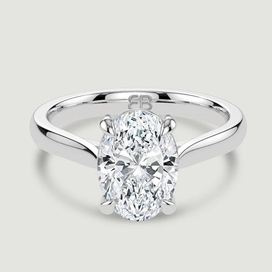 A platinum single stone diamond engagement ring, set with a lab-grown oval shape diamond held in a four claw setting. Viewed from above.