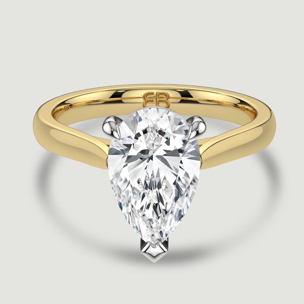 An 18ct yellow gold single stone diamond engagement ring, set with a lab-grown pear shape diamond held in a platinum three claw setting. Viewed from above.