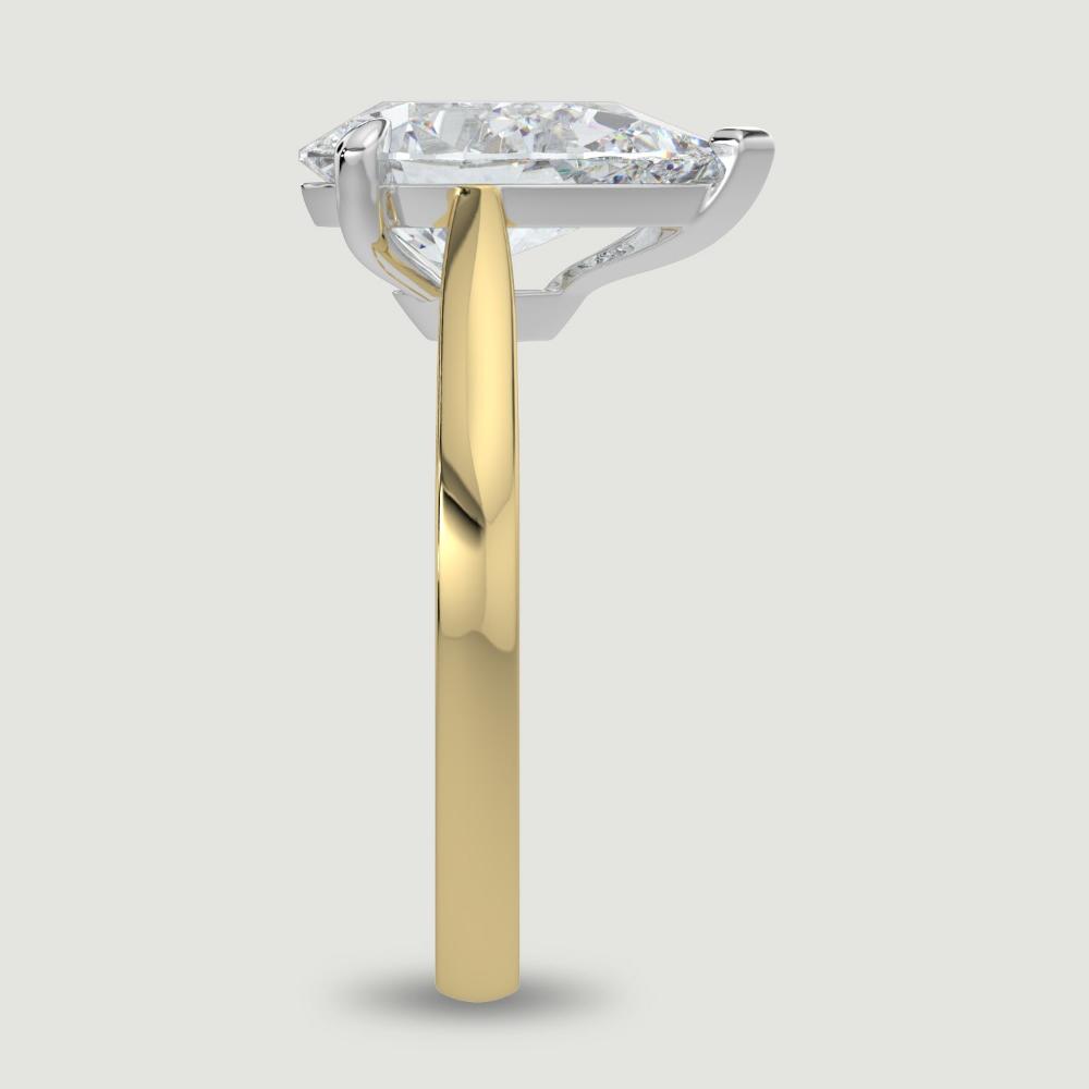 An 18ct yellow gold single stone diamond engagement ring, set with a lab-grown pear shape diamond held in a platinum three claw setting. Viewed from the edge.