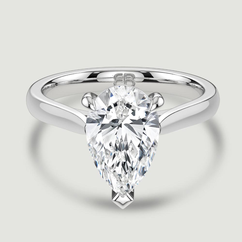 A platinum single stone diamond engagement ring, set with a lab-grown pear shape diamond held in a three claw setting. Viewed from above.