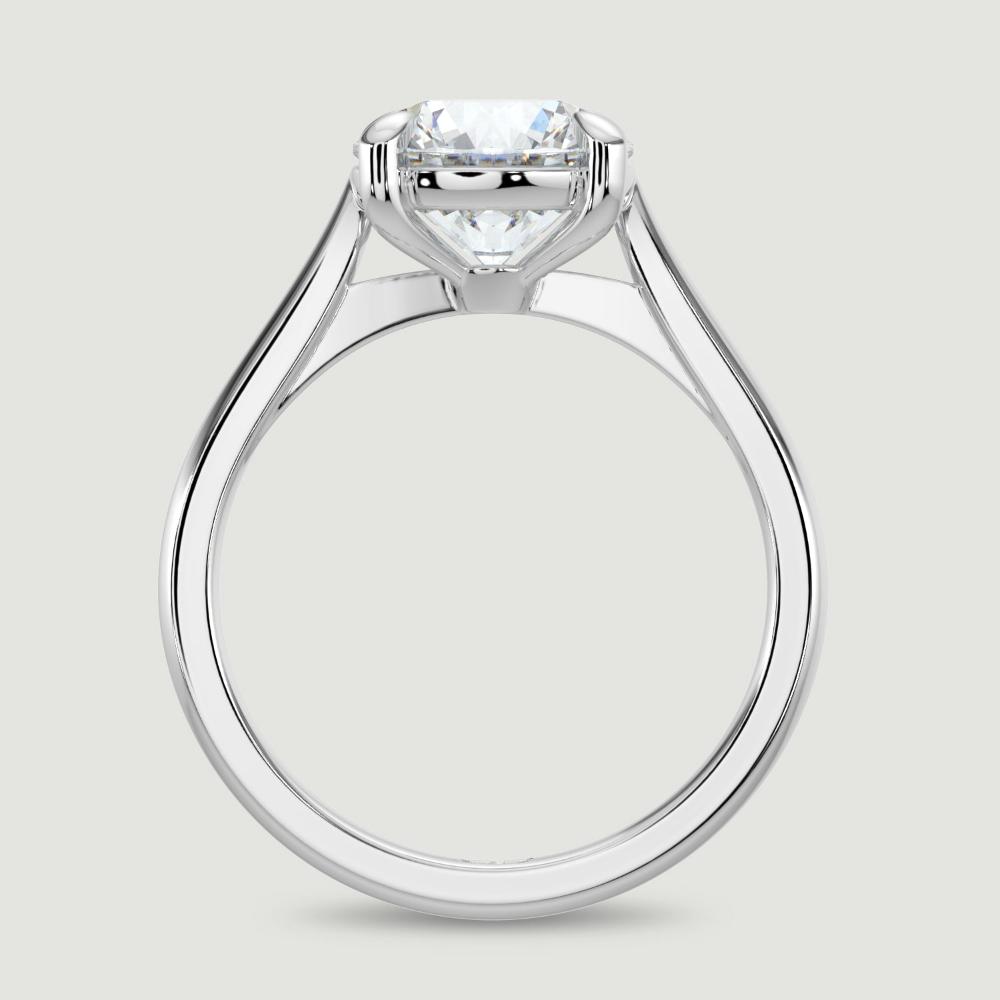 A platinum single stone diamond engagement ring, set with a lab-grown round brilliant diamond held in a four claw setting. Viewed from the side.