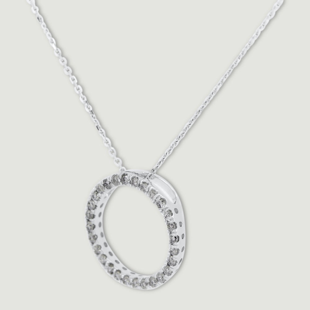 White gold diamond pendant, claw set with small round brilliant diamonds forming a circle 15mm in diameter, hanging on a fine chain - view from an angle