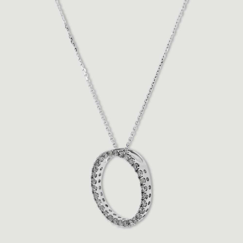 White gold diamond pendant, claw set with small round brilliant diamonds forming a circle 18mm in diameter, hanging on a fine chain - view from an angle