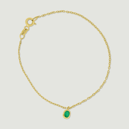 Yellow gold delicate bracelet with an oval charm rub over set with a single oval emerald - view of the whole bracelet