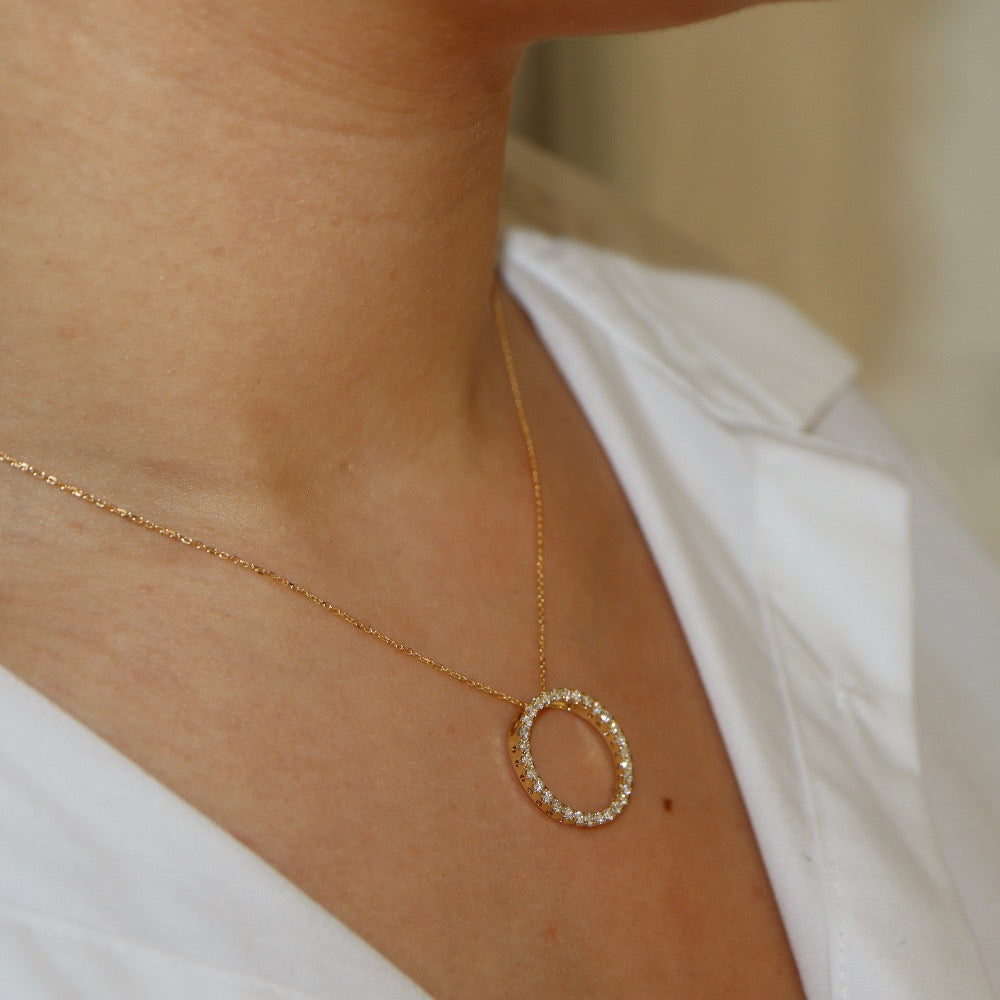 Yellow gold diamond pendant, claw set with small round brilliant diamonds forming a circle 18mm in diameter, hanging on a fine chain - photographed on model