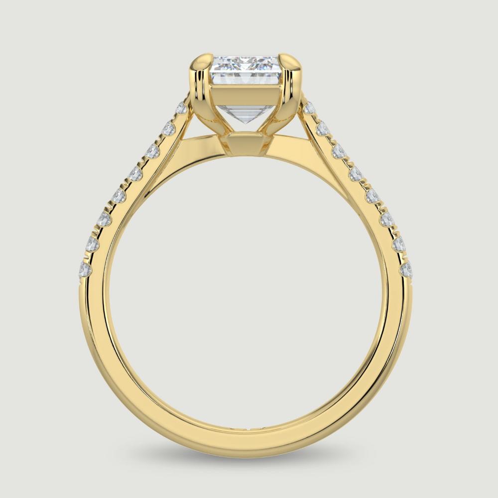 An 18ct yellow gold single stone diamond engagement ring, with micro-pavé set shoulders set with a lab-grown emerald cut diamond held in a four claw setting. Viewed from the side.