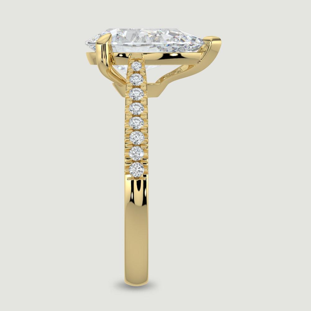 An 18ct yellow gold single stone diamond engagement ring, with micro-pavé set shoulders set with a lab-grown pear shape diamond held in a three claw setting. Viewed from the edge.