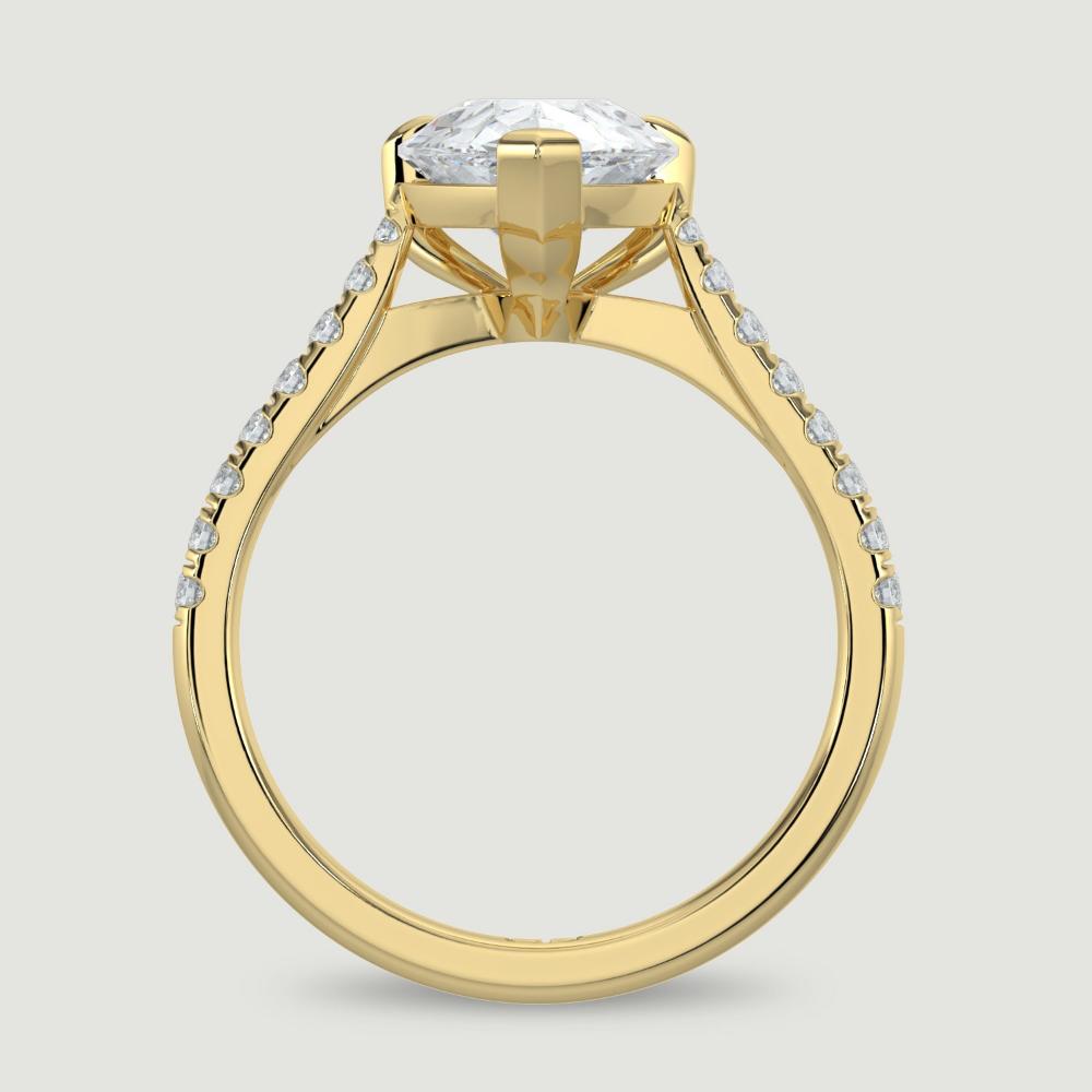 An 18ct yellow gold single stone diamond engagement ring, with micro-pavé set shoulders set with a lab-grown pear shape diamond held in a three claw setting. Viewed from the side.